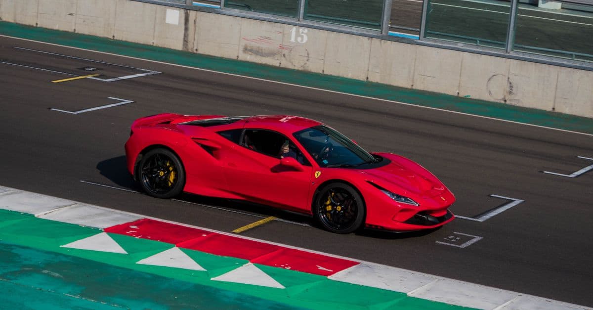 A red Ferrari on the track, shot from above as it drives along the straight in the pit lane