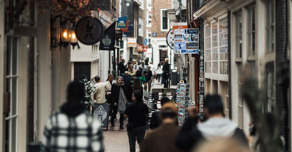 Una strada commerciale affollata in una città europea con persone che fanno acquisti, sabato 8 agosto 2026
